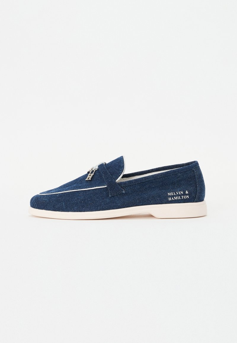 Marineblaue Denim-Slipper mit weißer Sohle, weißem Rand und "Melvin & Hamilton" Logo an der Fersenseite.
