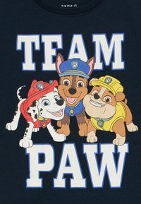 Navy t-shirt featuring three cartoon dogs with distinct colors: a black and white spotted dog in red, a brown dog in blue, and a yellow dog.