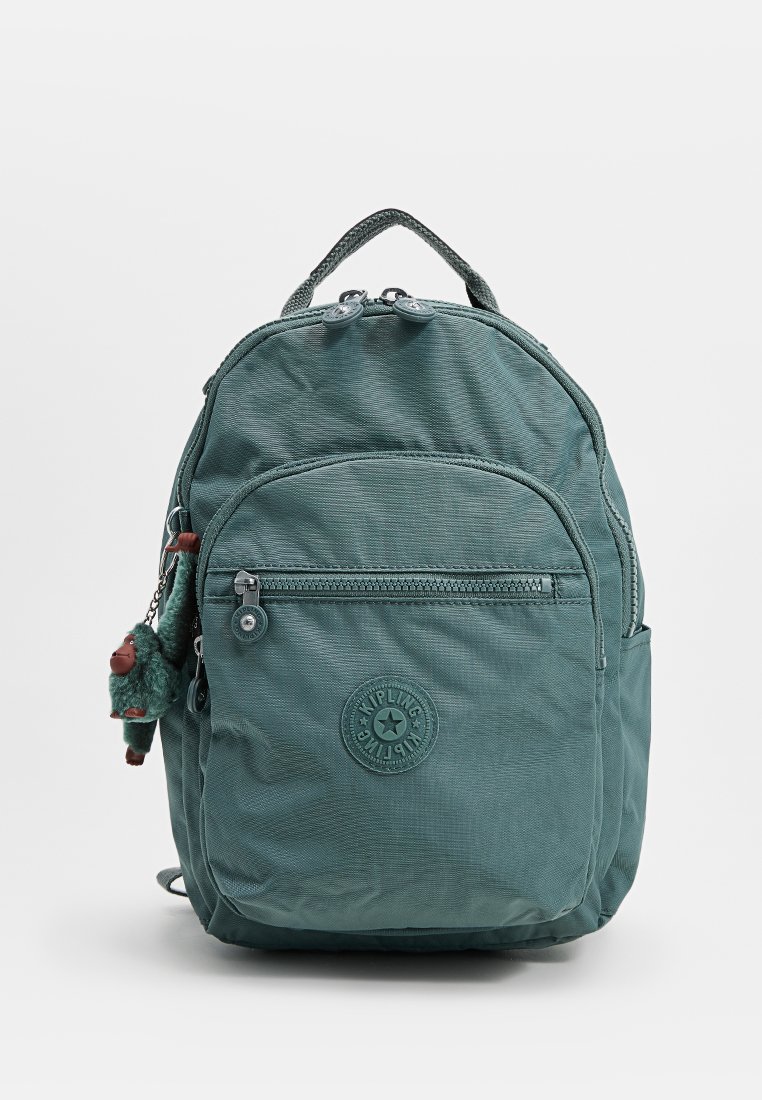 Mochila de tela en color teal con un bolsillo con cremallera en la parte frontal, parche con el logo de Kipling y un pequeño llavero de un mono de peluche adjunto al tirador de la cremallera lateral.