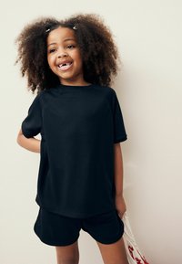 Zwarte sportshirt met korte mouwen en bijpassende shorts, gemaakt van ademend materiaal, met een relaxte pasvorm en ronde halslijn.