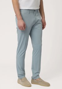 Lichtblauwe broek in een slim fit ontwerp, met een knoopsluiting, zijzakken en een gladde textuur. Gecombineerd met beige instappers.