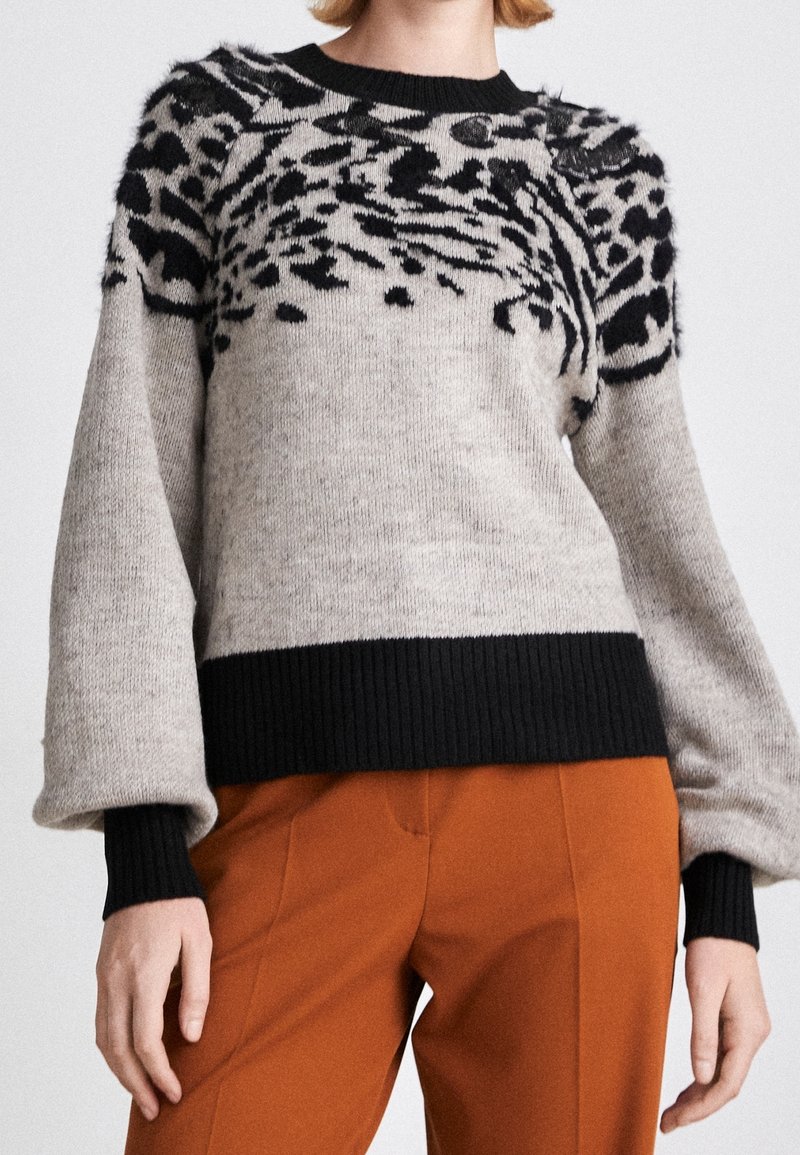 Knitted sweater featuring a gray body with a black animal print design on top, ribbed black cuffs and hem, and a relaxed fit.