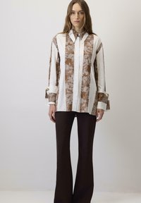 Košulja dugih rukava s uzorkom smešnih cvetova i belim prugama, s ovratnikom, dugim rukavima s kontrastnim manžetama, uparena s tamnosmešnim širokim pantalonama.