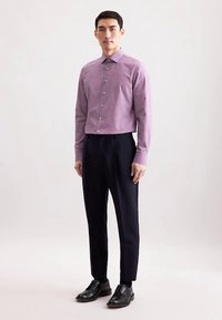 Fioletowa koszula w paski na długi rękaw z ostro zakończonym kołnierzykiem, z zapięciem na guziki z przodu, w połączeniu z dopasowanymi ciemnymi spodniami i czarnymi skórzanymi butami.