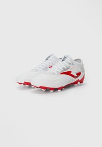 Ciorapi de fotbal albi cu accente roșii, având un material texturat, un design elegant și o talpă cu cuie pentru tracțiune pe iarbă.