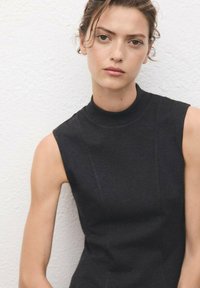 Black sleeveless mock-neck top with a fitted design and smooth texture, featuring subtle seam detailing. Background is plain white.