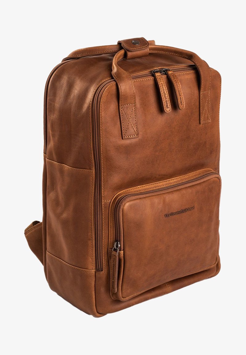Bruine leren rugzak met een rechthoekige vorm, voorzien van twee ritsen, zijvakken en een voorvak met rits voor opslag.