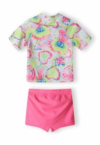 Plavkový top s krátkým rukávem s multibarevným tie-dye vzorem, v kombinaci s jednobarevnými růžovými šortkami. Oba vyrobeny z lehkého, stretchového materiálu.