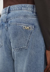 Jeans in denim chiaro con vita alta, dotati di un hardware con il logo dorato "MK" sulla tasca posteriore e un classico design a cinque tasche.
