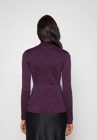 Fialový rolák s žebrovaným vzorem a přiléhavým střihem. Vyrobený z texturované látky s jemným třpytem. Dlouhé rukávy, bez viditelných zapínání.