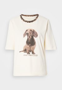 Krémové tričko s krátkymi rukávmi, ktoré má realistickú grafiku jazvečíka a výstrih s leopardím vzorom. Text znie "STAY PAWSITIVE."