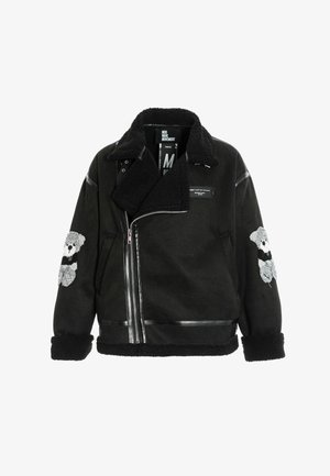 Chaqueta de forro polar negro con cremallera asimétrica, parches de oso de peluche en las mangas y cuello y puños texturizados.