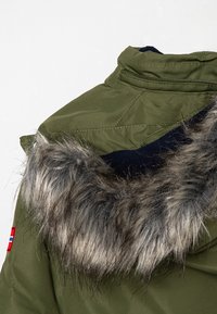 Green puffer jacket featuring a faux fur collar, a fitted design, and a visible navy inner lining with a small patch on the side.
