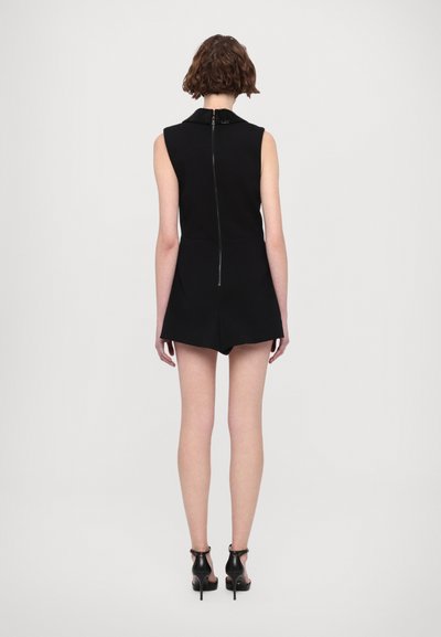 Schwarzer ärmelloser Jumpsuit mit einem hohen Kragen, Reißverschluss auf der Rückseite und tailliertem Design. Verfügt über eine Shorts mit glatter Textur.