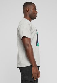 Camiseta de algodón gris con mangas cortas y un gráfico vibrante impreso en la parte frontal. Corte uniforme, textura suave y diseño casual.