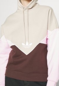 Hoodie med färgblock i beige, rosa och brunt, i bomullsblandat material, med logotyp framtill och snörningsdetaljer.