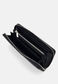 Portafoglio in pelle nera con chiusura a zip, diverse tasche e slot per carte, con finiture in metallo argentato e superficie liscia.
