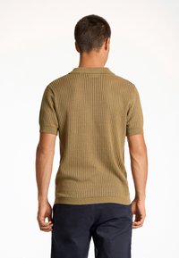 Strick-Polohemd in Olivgrün mit strukturiertem, perforiertem Design. Kurzärmel und Kragen; der Saum endet mit einem gerippten Akzent.