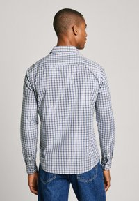 Camisa de cuadros de manga larga en blanco, azul y marino. Presenta un cuello estándar, puños con botón y dobladillo curvado. Fabricada con tela ligera.
