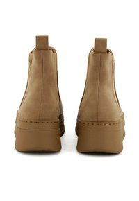 Stivaletti alla caviglia color beige con una finitura in suede liscia, caratterizzati da un design testurizzato sui lati, punta arrotondata e una suola piatta spessa.