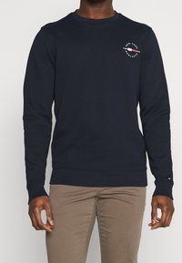 Felpa blu navy realizzata in morbido tessuto, con scollatura rotonda, maniche lunghe e dettaglio del logo sul petto. Vestibilità classica.