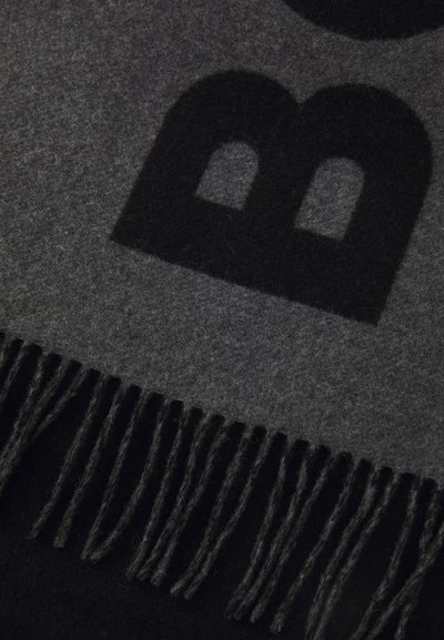 Écharpe en laine grise douce avec un motif foncé, bordée de franges. La texture semble chaude, idéale pour les temps froids.