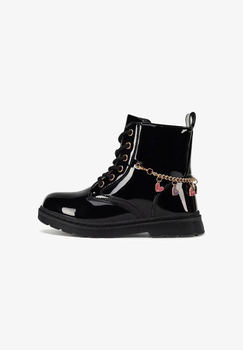 Botines de charol negro con ojales dorados, diseño con cordones, suela de goma y una cadena decorativa con dijes de corazones.