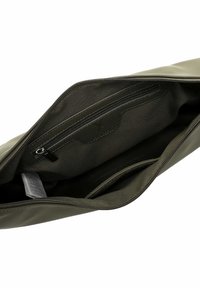 Interno di borsa verde oliva con texture liscia, dotato di tasca con zip, tasca a scivolo e un'etichetta. Foderato con tessuto scuro.