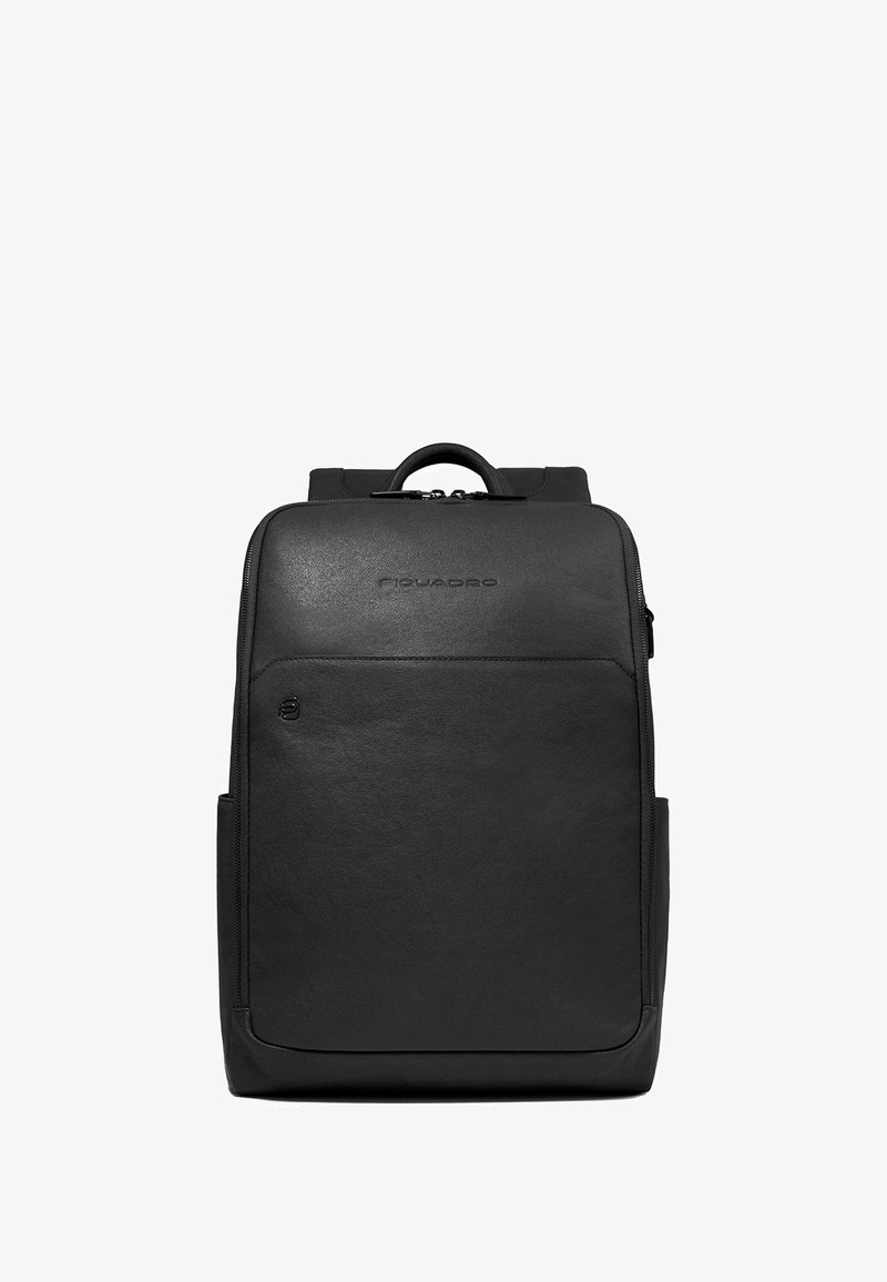 Mochila de cuero negro con textura suave, equipada con asa superior, cierre de cremallera y bolsillo frontal. Logotipo sutil exhibido en la parte delantera.