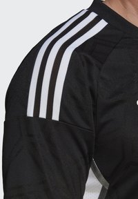 Black sports jersey featuring three horizontal white stripes on the shoulder, textured fabric, and subtle geometric patterns.