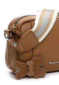 Brązowa, teksturowana skórzana torba na ramię z plecionym paskiem w paski w odcieniach szarości, bieli i beżu. Zawiera ozdobę w kształcie misia ze skóry.