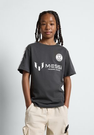 Graues T-Shirt mit kurzen Ärmeln aus Baumwolle, mit weißen Grafiken, darunter "MESSi" und einem runden Logo auf der Brust, kombiniert mit beigen Cargo-Shorts.