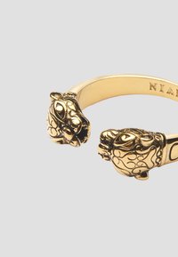 Guldtonet armbånd med to løvehoved accenter med detaljeret udsmykning. Glat bånd med poleret finish, der måler cirka 6,4 cm i bredden.