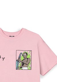 Camiseta de algodón rosa con un gráfico de un músico tocando el saxofón, contorneado en negro con acentos en verde y un fondo de llamas.