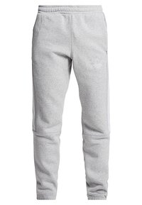 Ljust grå sweatpants med elastisk midja, smalnande ben, sidostripes och broderad Adidas trefoil-logga på vänster lår.