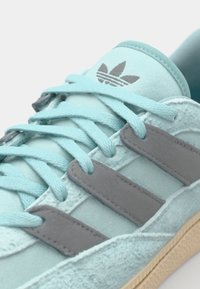 Minta zaļa zamšsneakers ar pelēkiem ādas svītrām un saskaņotām kurpēm, ar tekstūru zoli un logotipu uz mēles.