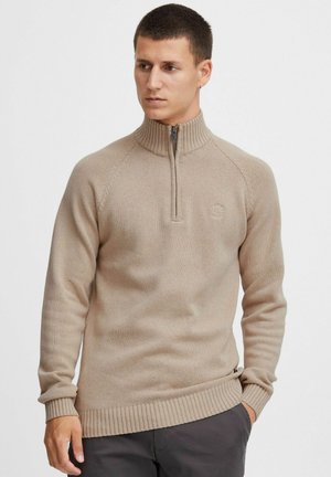 Beige Pullover mit Reißverschluss und Rippbündchen sowie -saum. Strickstruktur, mit einem dezenten Logo auf der Brust und Raglansärmlen.