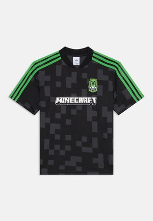 Sort og mørkegrå pixeleret t-shirt med grønne skulderstriber, hvid "Minecraft"-logo i midten og grønt Creeper-emblem på brystet.