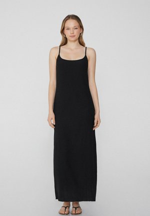 Robe maxi noire avec de fines bretelles spaghetti, un décolleté en scoop et une silhouette droite, fabriquée à partir d'un tissu lisse et léger.