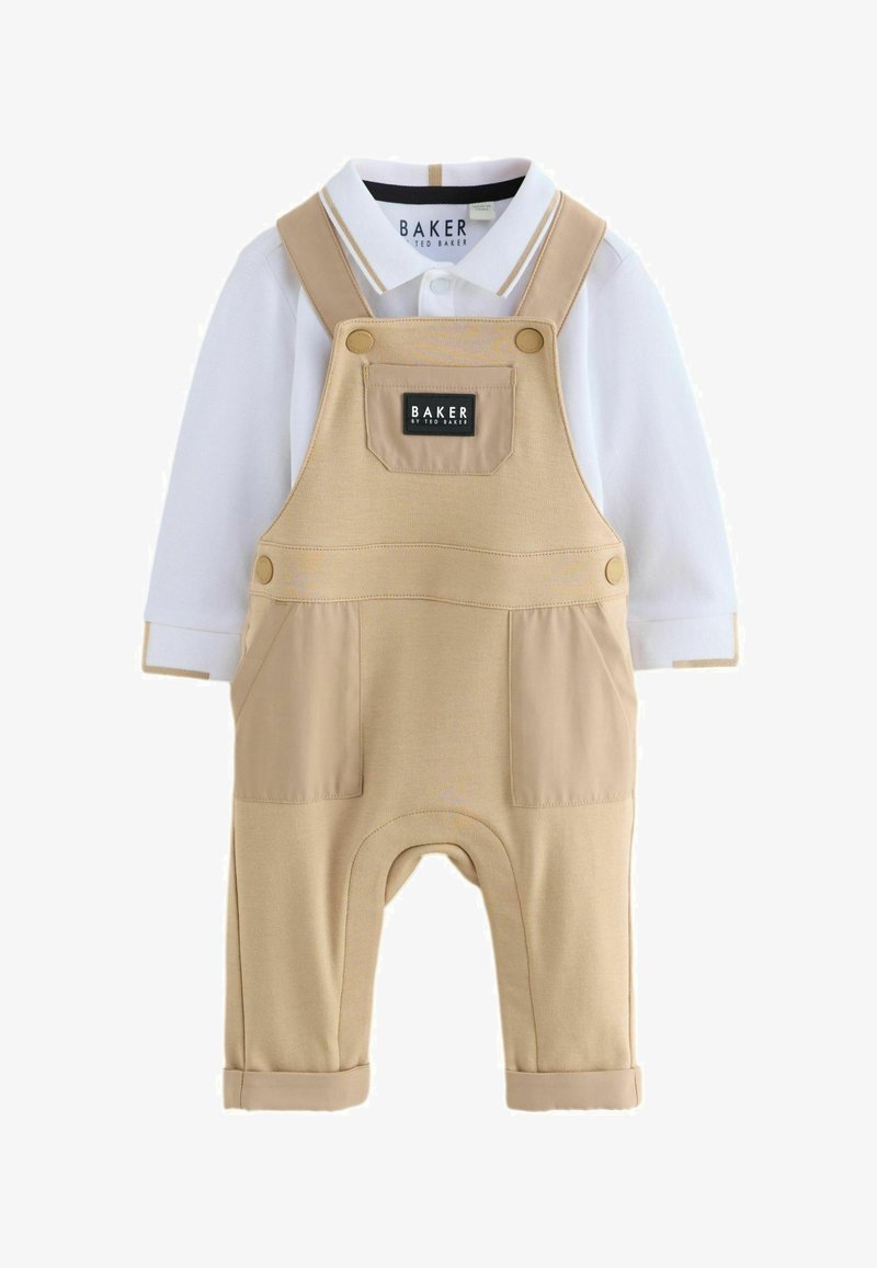 Salopette beige pour tout-petit avec poches avant portée sur un polo à manches longues blanc avec des bordures beige au col et aux poignets.