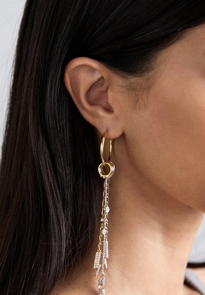 Gold hoop earrings feature a chain with crystal accents, showcasing a combination of shiny metal and sparkling details.