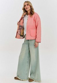 Růžová prošívaná bunda s boční kapsou a vzorovanou podšívkou. Široké světle modré džíny s třepeným lemem a slip-on boty s potiskem zvířat.