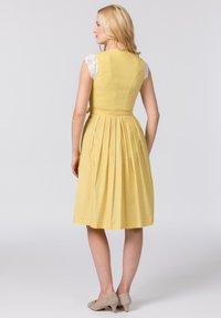 Gelbes ärmelloses Kleid mit Spitzenärmeln, gefaltetem Rücken und tailliertem Oberteil. Weicher Stoff mit dezentem Muster und gebundenem Taillendetail.