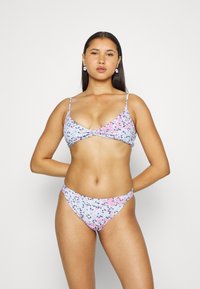 Conjunto de biquíni floral com um fundo azul claro e padrões de flores pink e pretas. O top possui alças finas e detalhe em nó.