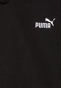 Tessuto felpato nero con logo "PUMA" ricamato in bianco, caratterizzato dalla silhouette di un puma che salta. Texture morbida, design casual.