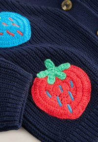Marineblaues Strickgewebe mit bunten gehäkelten Erdbeer- und blauen Obst-Applikationen sowie sichtbaren braunen Knöpfen.