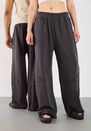 Pantalons à jambe large gris foncé dotés d'un tissu doux, d'une taille élastique et de découpes au niveau des genoux avec des bords effilochés. Assortis à des sandales à plateforme.