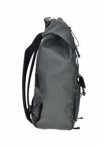 Mochila de tela gris con superficie texturizada, que cuenta con un bolsillo lateral, correas ajustables y cierre de cremallera.