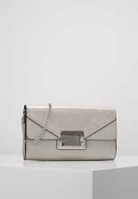 Stříbrná kabelka s texturou, s klopou, ozdobená metalickým zapínáním, řetízkem a hladkým béžovým základem.