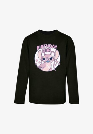 Must have pikkade varrukatega must särk, millel on karikatuuritegelane, ümmargune graafika tekstiga "SÜNNIPÄEVA TÜDRUK" ja pastellist tähed valgel taustal.